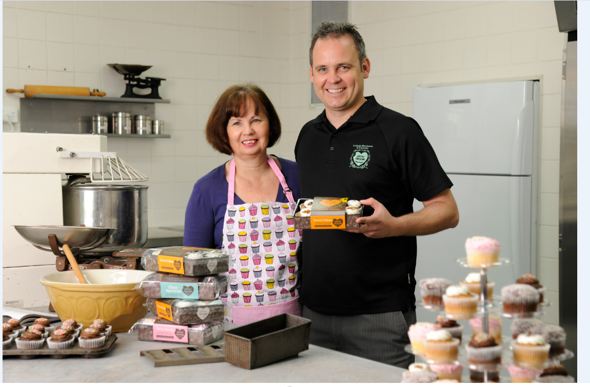 June and Carl stand in a kitchen surrounded by delicious cupcakes